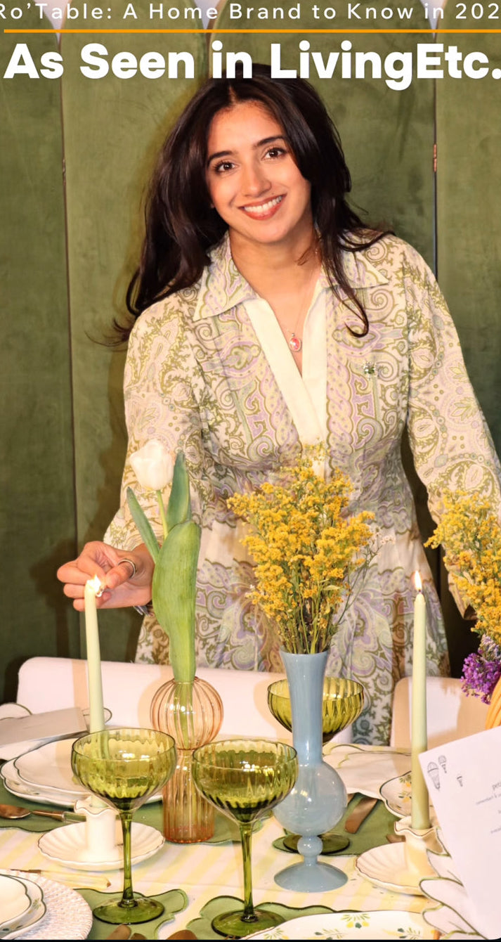Woman arranging flowers at a table with decorative elements, featuring text about a home brand.