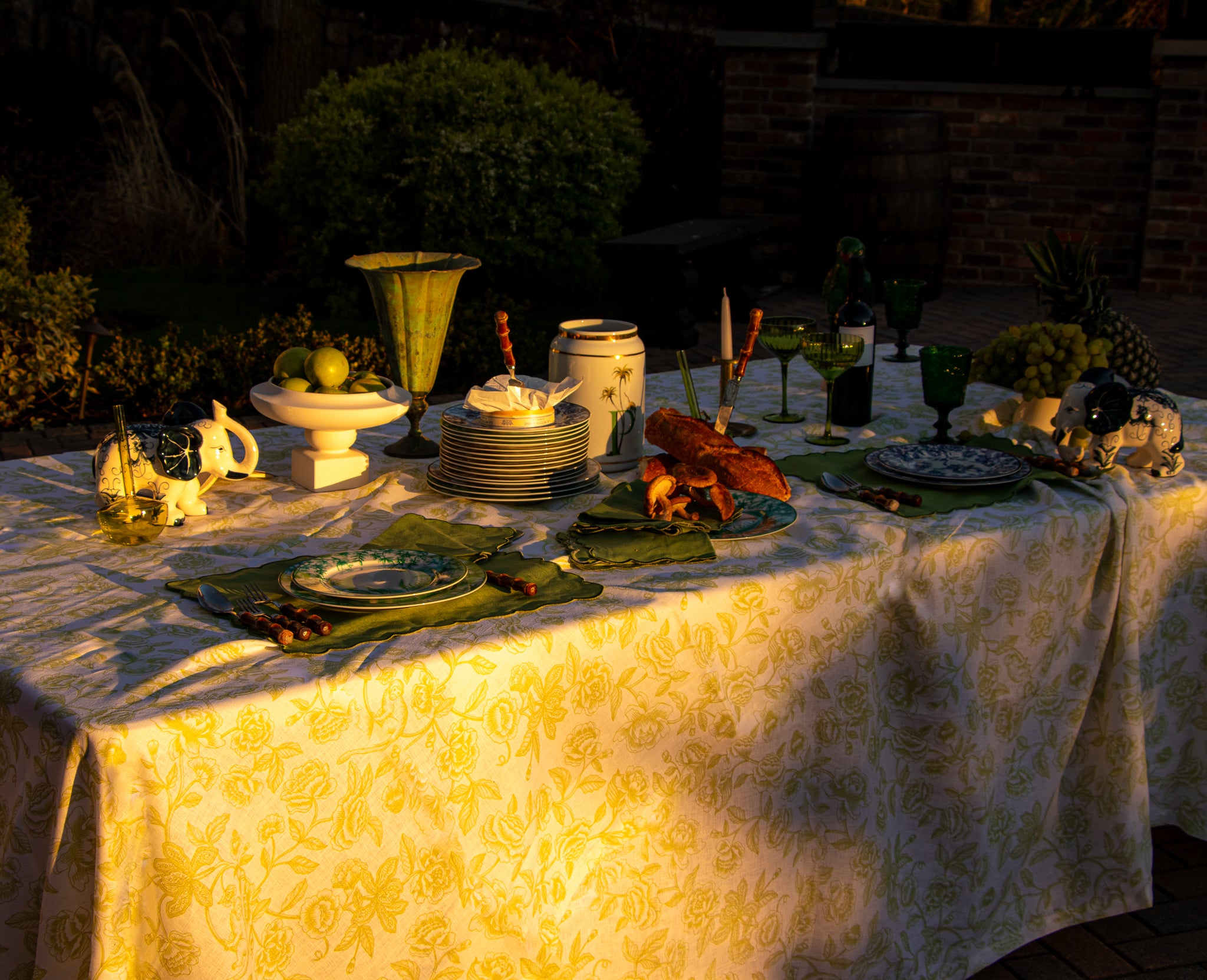 Sun lights up safari table with white linen featuring a delicate pistachio green design of subtle monkeys and floral patterns