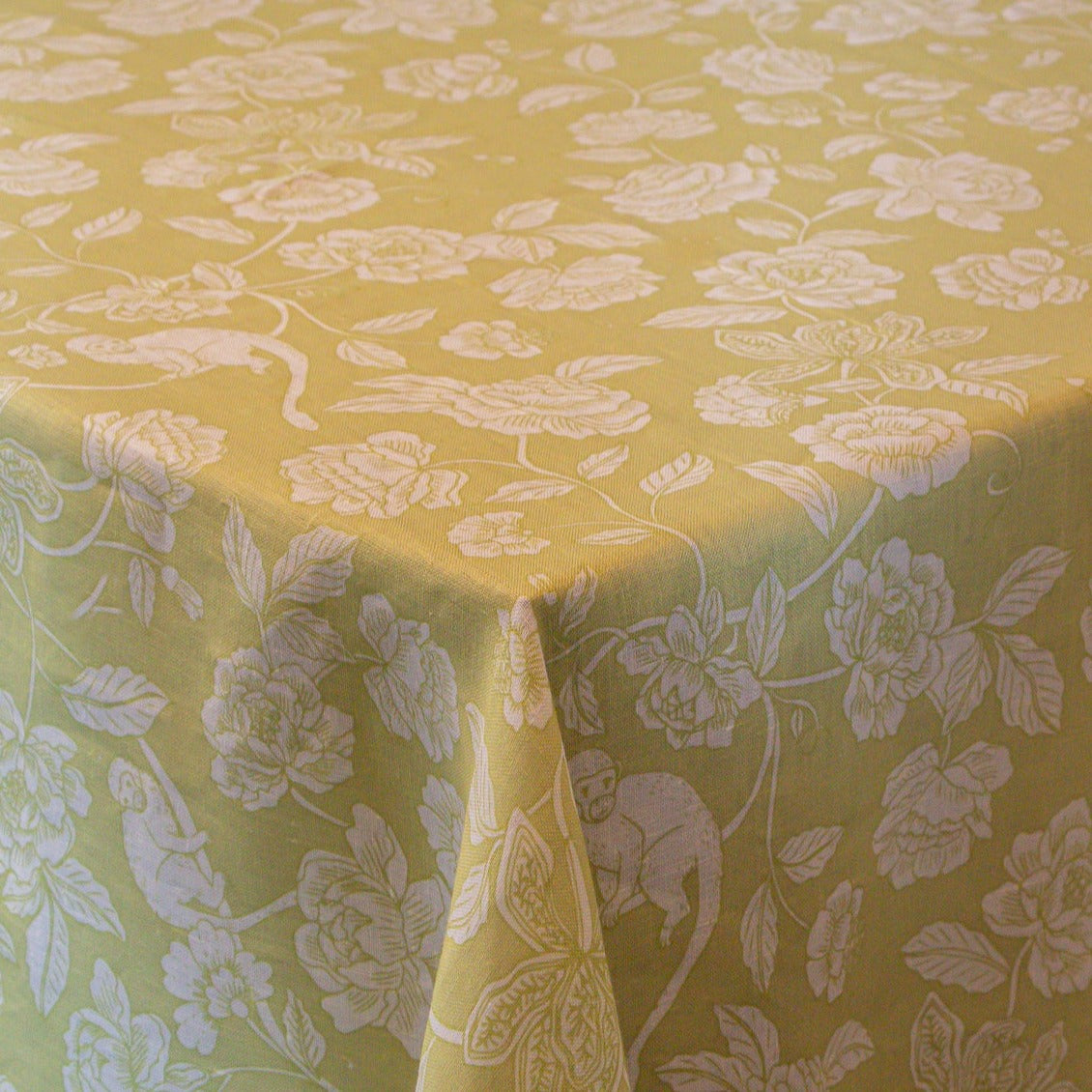 Pistachio Green tablecloth in linen, featuring a delicate white design of subtle monkeys and floral patterns