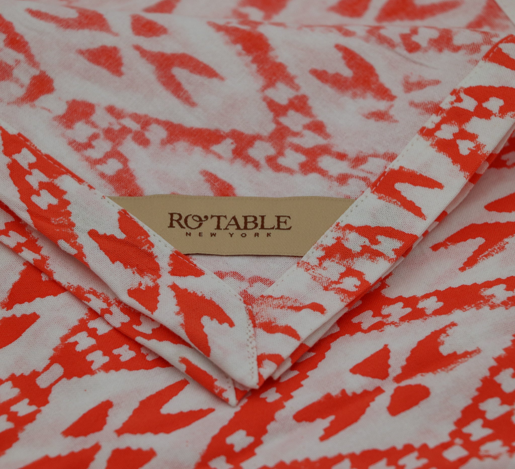 A Cotton Tablecloth by Ro'Table NYC in Tangerine-coral. Hue and print, reminiscent of radiant sunsets and vibrant coral reefs