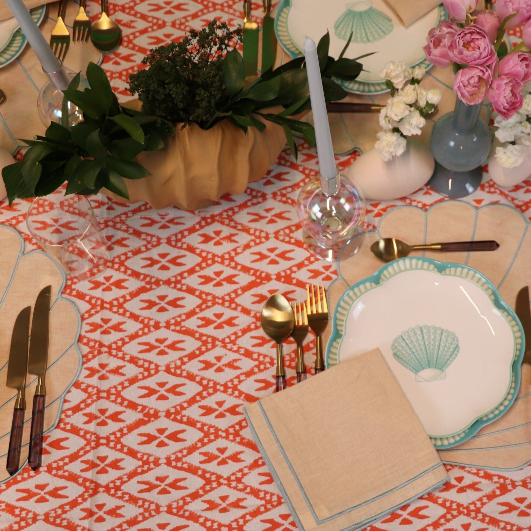 A coastal sea shell table setting. Cotton Tablecloth in Tangerine-coral. Hue and print, reminiscent of radiant sunsets and vibrant coral reefs